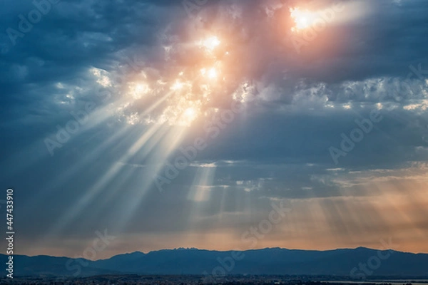 Fototapeta Beam of light through the clouds. Rays of light shining through clouds. Celestial entity over the city. Sign of presence of God in some religions. Ultraviolet rays concept.