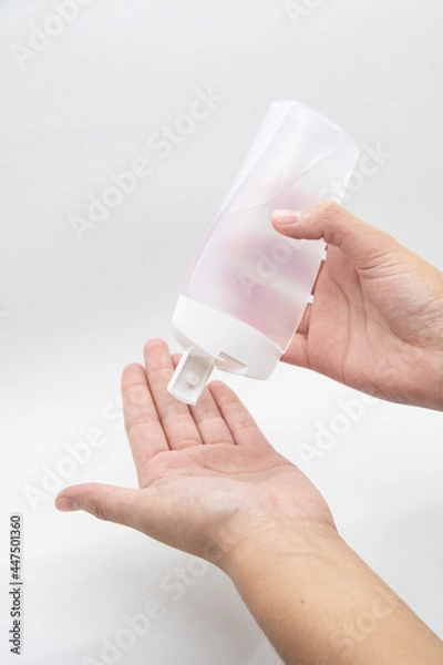 Fototapeta Hands using a plastic bottle of sanitizer