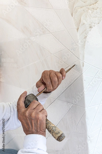 Fototapeta Detail of artist's hands sculpting marble with hammer and chisel