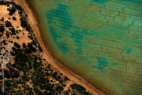 Obraz Abstract aerial view of blue-green water in shifting red deposition of sediment gradually moving through alluvial plains of Francois Peron National Park in Western Australia.