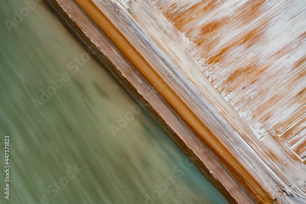Obraz Abstract aerial view of blue-green water in shifting red deposition of sediment gradually moving through alluvial plains of Francois Peron National Park in Western Australia.