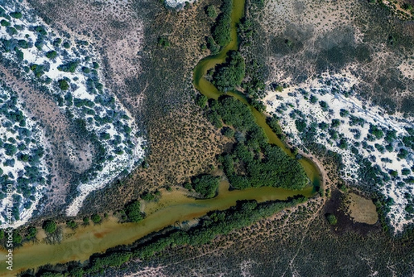 Obraz Abstract aerial view of blue-green water in shifting red deposition of sediment gradually moving through alluvial plains of Francois Peron National Park in Western Australia.