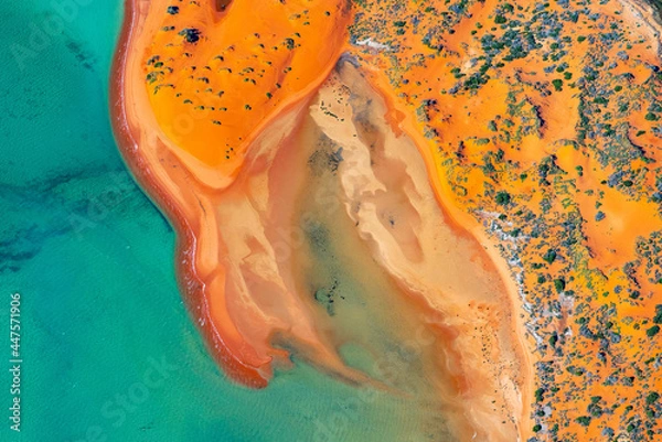 Obraz Abstract aerial view of blue-green water in shifting red deposition of sediment gradually moving through alluvial plains of Francois Peron National Park in Western Australia.