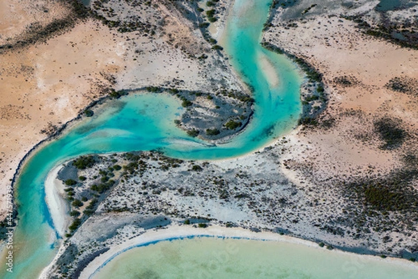 Fototapeta Abstract aerial view of blue-green water in shifting red deposition of sediment gradually moving through alluvial plains of Francois Peron National Park in Western Australia.