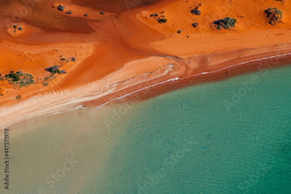 Obraz Abstract aerial view of blue-green water in shifting red deposition of sediment gradually moving through alluvial plains of Francois Peron National Park in Western Australia.