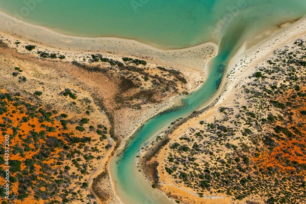 Obraz Abstract aerial view of blue-green water in shifting red deposition of sediment gradually moving through alluvial plains of Francois Peron National Park in Western Australia.