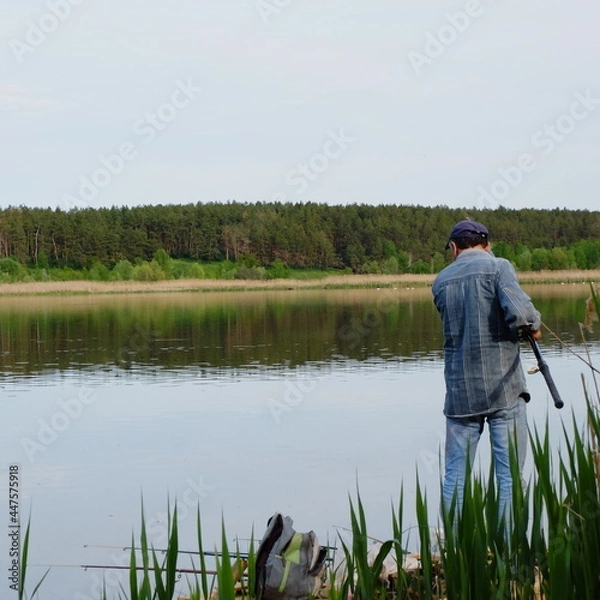 Obraz fisherman with a lot of fishing rods on the river in spring
