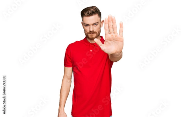 Fototapeta Young redhead man wearing casual clothes doing stop sing with palm of the hand. warning expression with negative and serious gesture on the face.