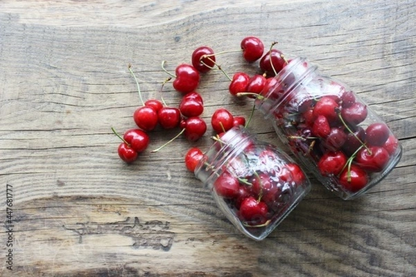 Fototapeta Merry. Berries in a jar on a wooden background. The concept of home preparations.