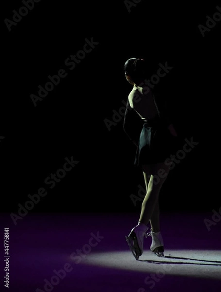 Fototapeta Ice skater with a beautiful pose illuminated with artistic light