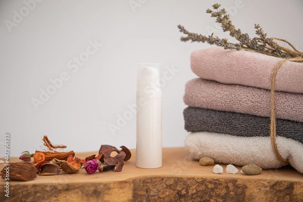 Obraz cosmetic product on wood.
folded towel and a few dried flower petals.
white background soft composition, relaxing and clean.
Empty label area suitable for mockup