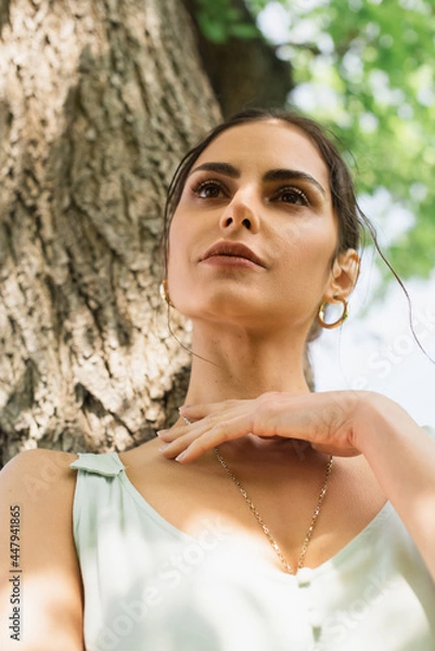 Fototapeta low angle view of pretty woman looking away in park
