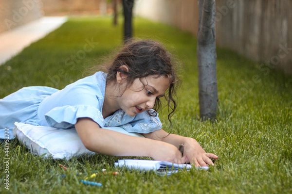 Obraz Little girl lying on the grass. studying in  the backyard