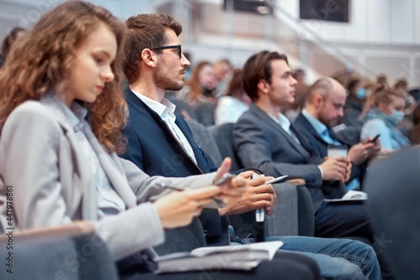 Obraz young business people using their smartphones during the workshop.