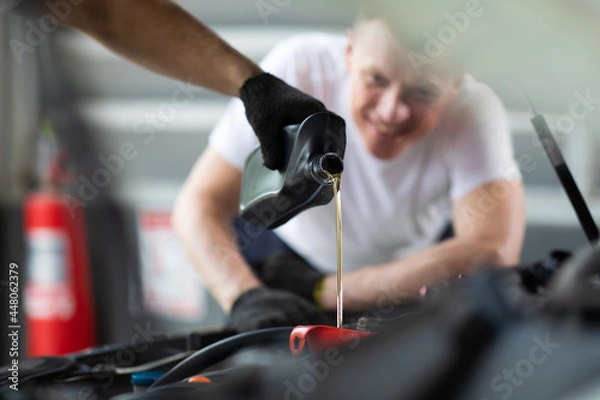Fototapeta Pouring oil to car engine. Closue up male mechanic hand working  and service in Car Service station