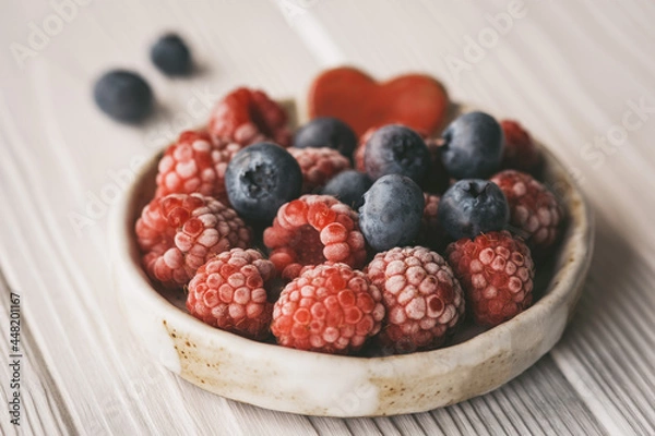 Fototapeta raspberries and blueberries in a small ceramic bowl