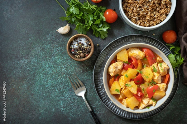 Fototapeta The concept of Diet menu. Homemade turkey or chicken with pineapple sauce and boiled spelled on a dark stone table. Top view flat lay background. Copy space.