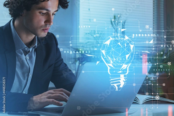 Fototapeta Businessman browsing internet via laptop at office workplace to find new ideas for start up. Blue digital hologram of light bulb. Concept of creativity and brainstorming