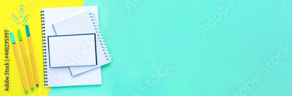 Fototapeta Banner. Stack of notebooks on a spiral overlap. Bright, colorful yellow with mint color background. Back to school concept. Copy space, top view, flat lay.