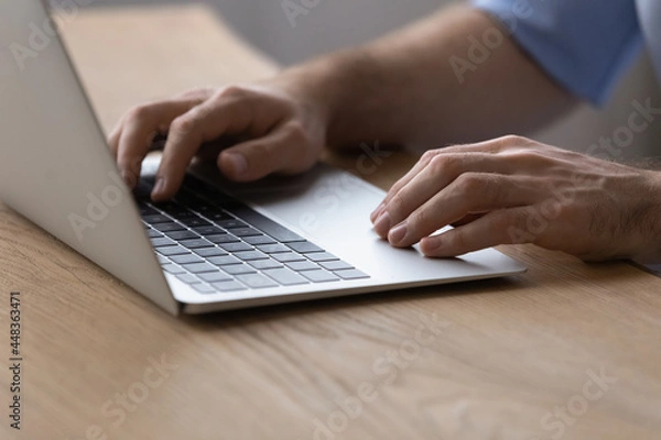 Fototapeta Working on laptop. Close up of millennial male hands typing text on modern notebook computer keyboard. Young man user browse web search information online prepare electronic report check email on pc