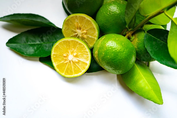Fototapeta Limes,Half of lime citrus fruit, which is typically round, green in color with leafs  on isolated white background.Lime juice is used to make limeade and as an ingredient in many cocktail.