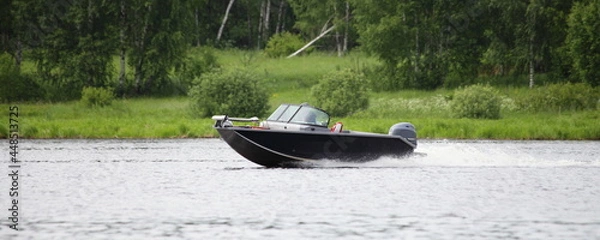 Fototapeta Fast gliding Russian fishing motor boat side view on green trees on far shore background in Tver ragion at summer day, active recreation boating tourism on Volga river
