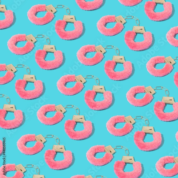 Fototapeta Colorful pattern with pink furry handcuffs on serenity pastel blue background.