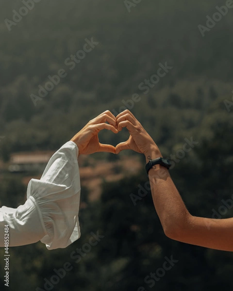 Fototapeta Heart shape made by hands of two girls with naturte in the background.