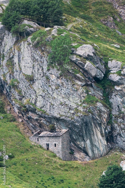Obraz Mountain house in the middle of the alps. Summer in the green mountain with a little house. Alpine mountains with a play of light and shadow of the clouds.