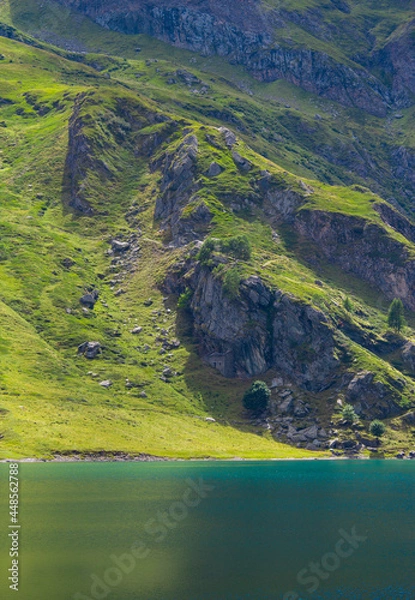 Obraz Mountain lake in the middle of the alps. Summer in the green mountain with a blue lake. Alpine mountains with a play of light and shadow of the clouds.