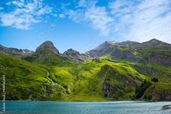 Obraz Mountain lake in the middle of the alps. Summer in the green mountain with a blue lake. Alpine mountains with a play of light and shadow of the clouds.