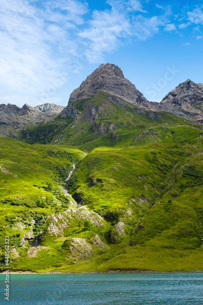 Obraz Mountain lake in the middle of the alps. Summer in the green mountain with a blue lake. Alpine mountains with a play of light and shadow of the clouds.