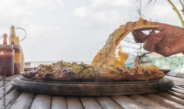 Obraz Hand lifting a slice of pepperoni pizza.