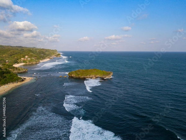 Obraz Drone photo of the beach with overgrown by lush green trees with waves rolling towards the shoreline and coral islands off the coast