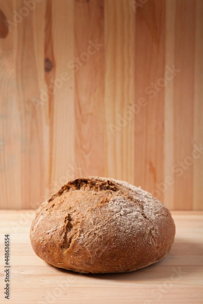Obraz Handmade fresh wheat bread on wooden background in the morning light. vertical frame side view with space area for text or design