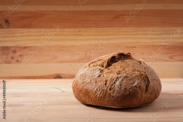 Obraz Handmade fresh wheat bread on wooden background in the morning light. horizontal frame side view with space area for text or design
