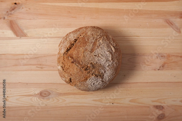 Obraz Handmade fresh wheat bread on wooden background in the morning light. horizontal frame top view with space area for text or design