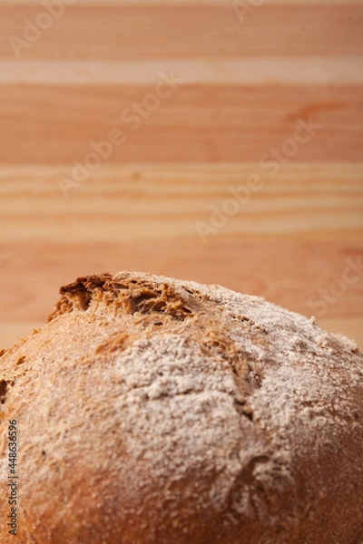 Obraz Handmade fresh wheat bread on wooden background in the morning light. vertical close-up frame side view with space area for text or design.
