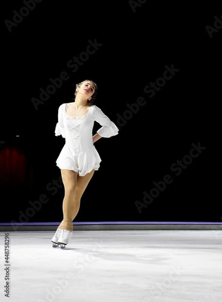Fototapeta Ice skater with a beautiful pose wearing white dress and showing her dedication to acting