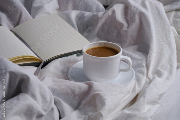 Fototapeta Coffee with milk and a notebook in bed. Breakfast in bed. Interior. Cosiness.