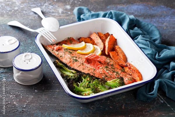 Obraz Baked sockeye salmon fish fillet with roasted sweet potato and broccoli, in enameled baking dish, selective focus