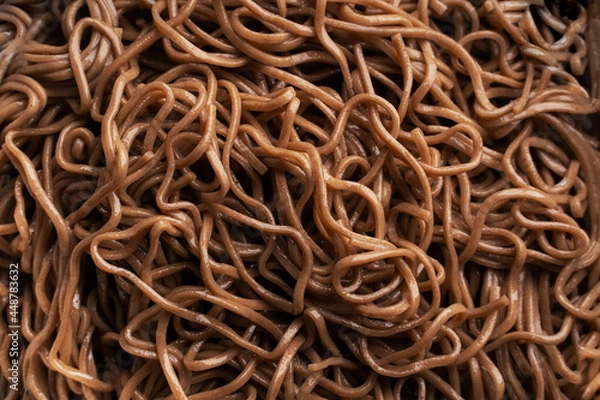 Obraz The texture of buckwheat or dark noodles. Brown noodles are visible throughout the frame. An ingredient for making a wok. Asian food. Asian pasta. Cooking food. Strid food. Gluten-free fries. 