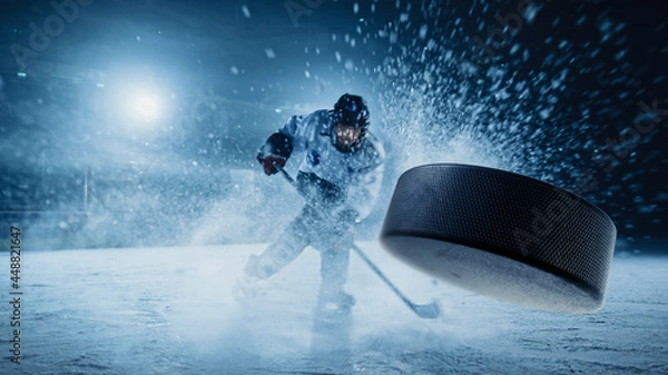 Obraz Ice Hockey Rink Arena: Professional Player Shooting the Puck with Hockey Stick. Focus on 3D Flying Puck with Blur Motion Effect. Dramatic Wide Shot, Cinematic Lighting.