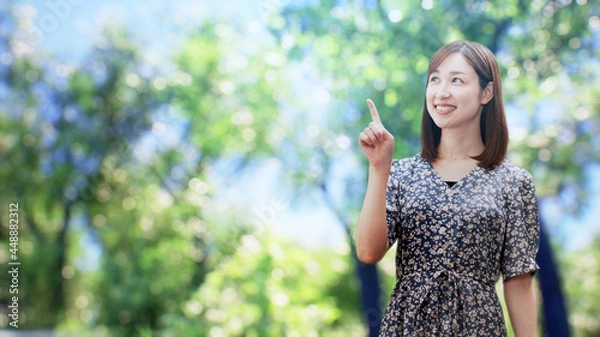 Fototapeta 木々の前に立つワンピースを着た女性