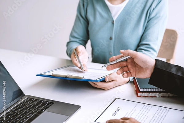 Fototapeta Close-up of a businessman holding a pen read the terms of signing contract documents at the office.