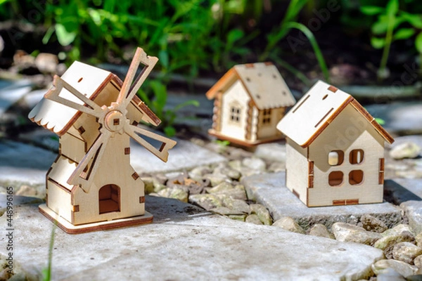 Fototapeta toy houses on a stone slab with greenery background