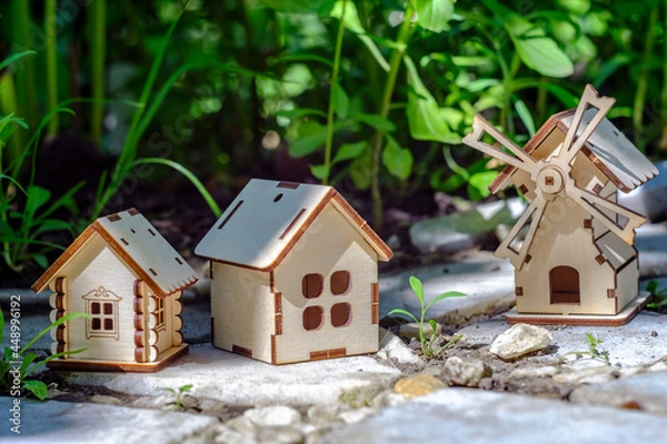 Fototapeta toy houses on a stone slab with greenery background