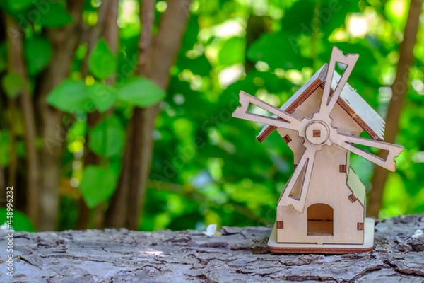 Fototapeta toy mill on a log with greenery background