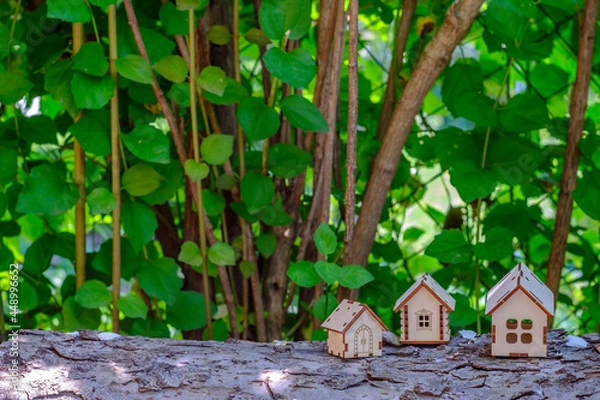Fototapeta small houses on a log with a background of greenery