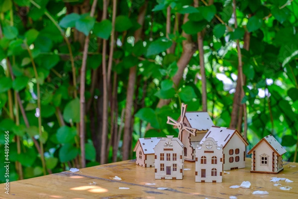 Fototapeta small houses on a wooden table with a background of greenery